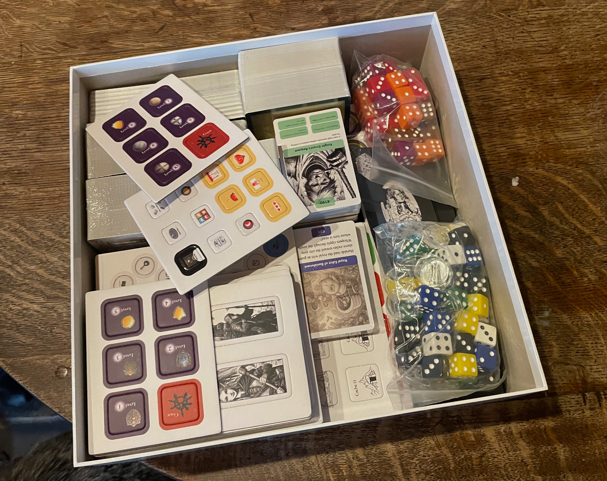 Open prototype game box containing cards, tokens, dice and other components for The Hidden Territories.